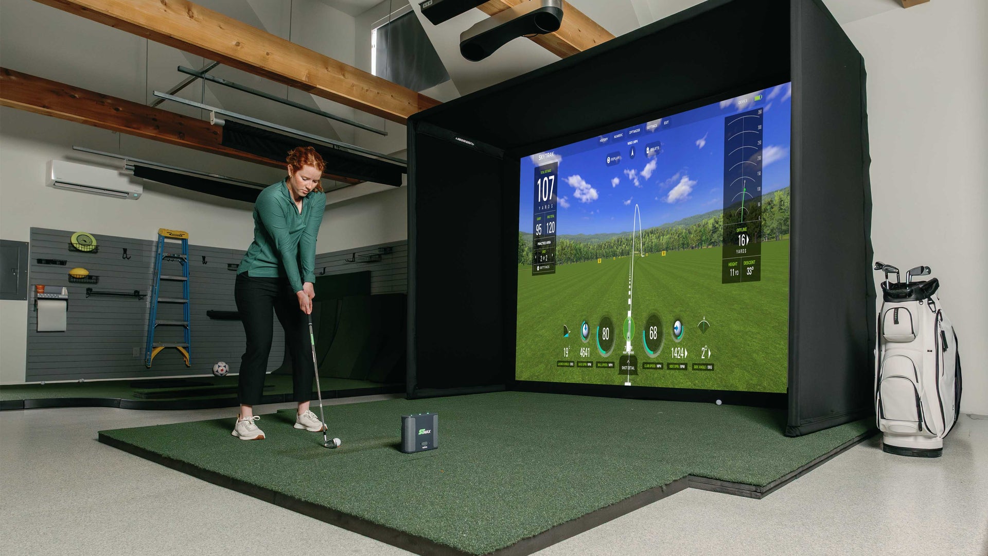 Golfer with SkyTrak ST Max launch monitor and golf simulator enclosure. 