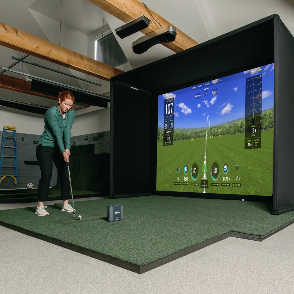 Golfer with SkyTrak ST Max launch monitor and golf simulator enclosure. 