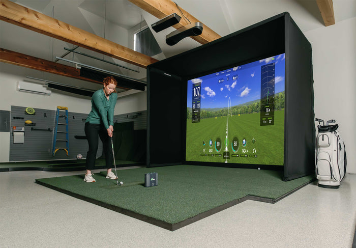 Golfer with SkyTrak ST Max launch monitor and golf simulator enclosure. 