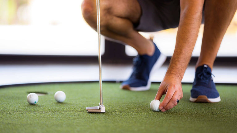 Golfer using putting green, setting up putt