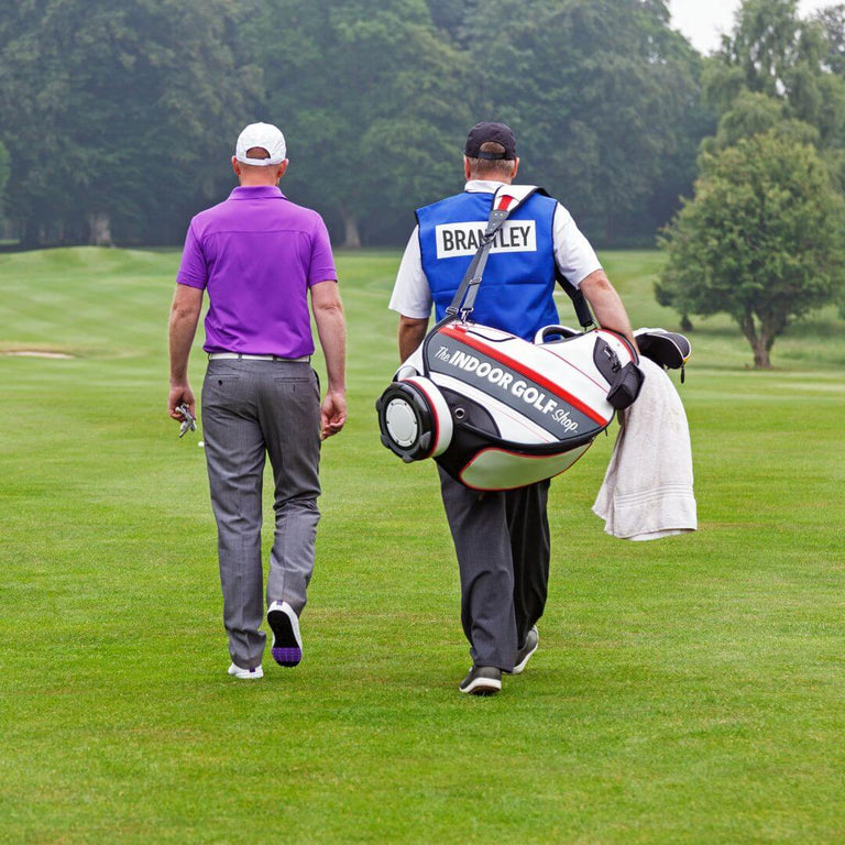 Golfer and caddie walking down fairway.