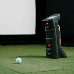 Uneekor EYE MINI Launch Monitor next to golf ball on SIGPRO Golf mat.