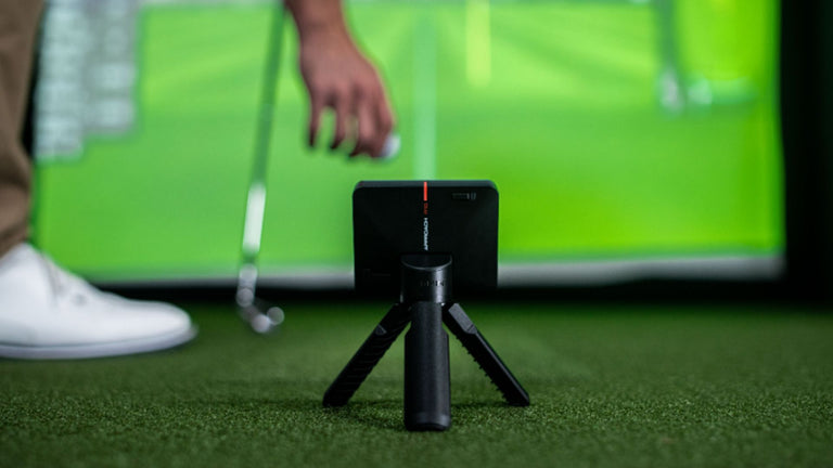 Garmin Approach R10 Launch Monitor with golfer placing golf ball on hitting surface.